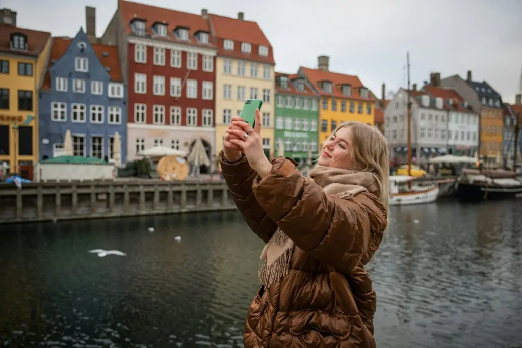 A tourist takes a selfie while in Nyhavn canal in the Danish capital, Denmark tourism concept.