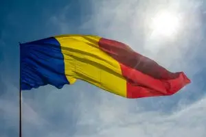Beautiful low angle shot of the Romanian flag waving on a sunny bright sky background