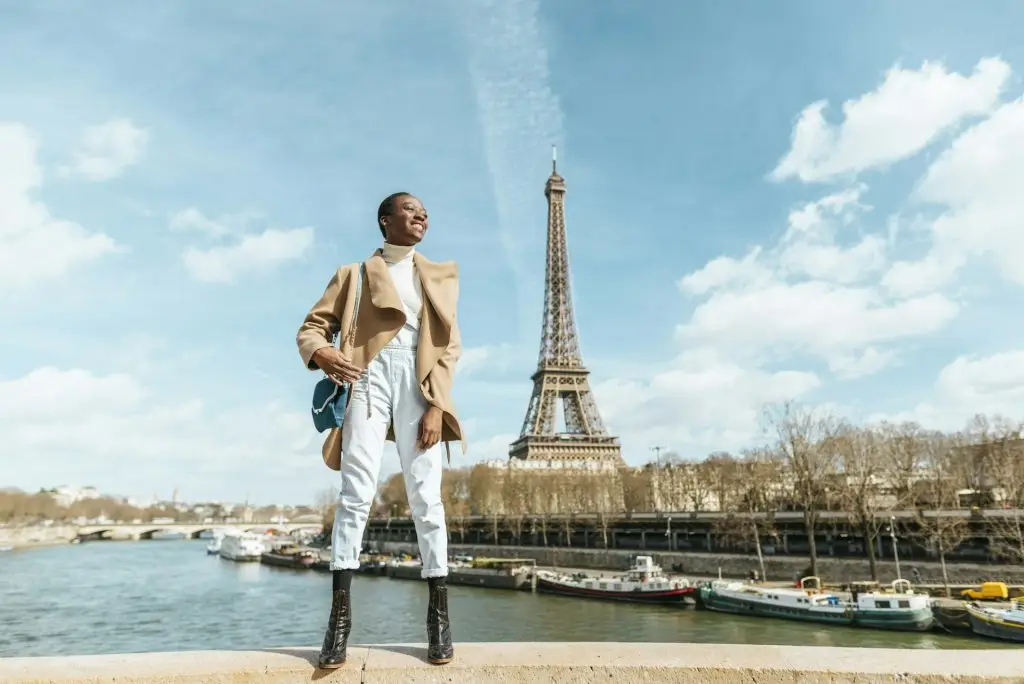 France, Paris, Smiling woman standing on a bridge with the Eiffel tower in the background