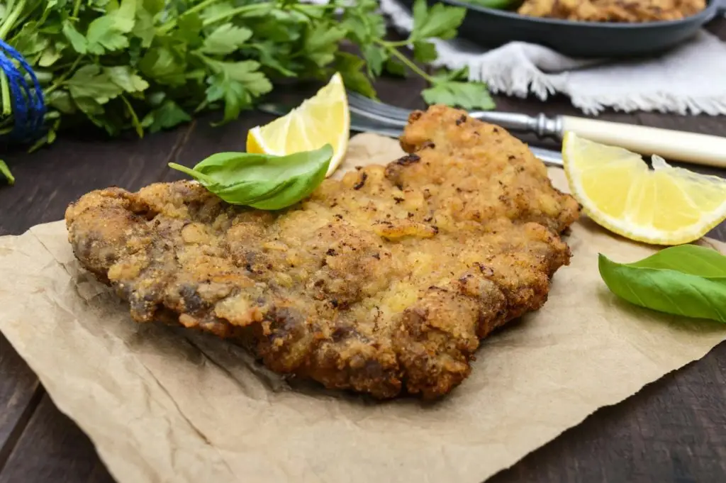 Homemade "Vienna" schnitzel on the wooden background. A traditional dish of Austrian cuisine.