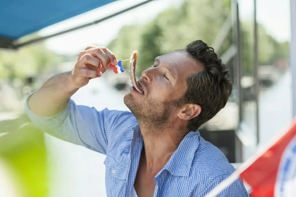 Netherlands, Amsterdam, man eating matjes herring