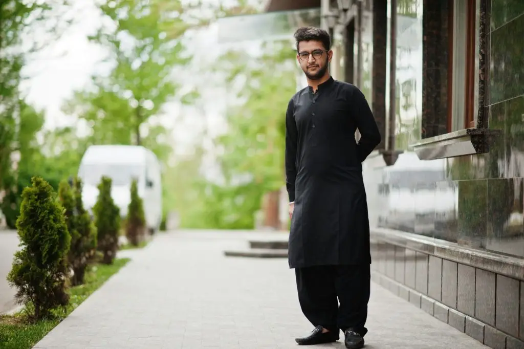 Pakistano bangladesh man wear black traditional clothes and eyeglasses pose outdoor.
