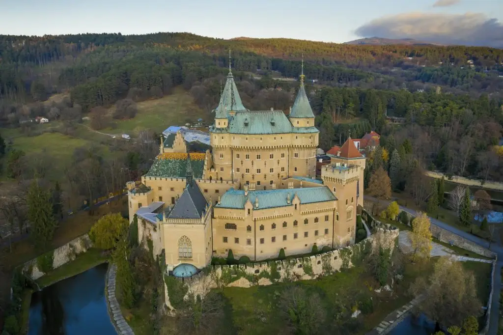 Aerial view of Bojnice castle in Slovakia guarded by its moat and surrounded by forest