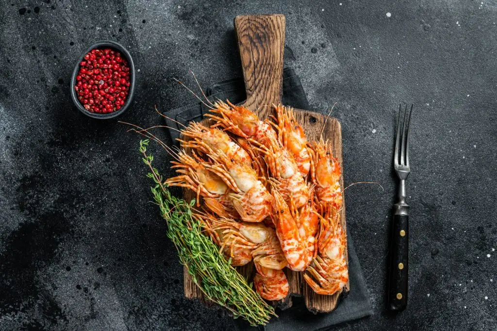 Cooked Greenland Prawn Shrimp on a wooden board. Black background. Top view
