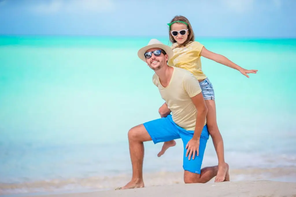 Family at tropical beach walking together in caribbean island of Antigua and Barbuda