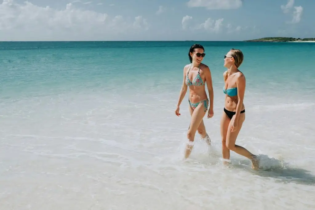 Two mid adult sisters strolling in blue sea, Anguilla, Saint Martin, Caribbean