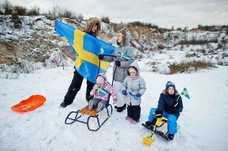 Scandinavian family with Sweden flag in winter swedish landscape.