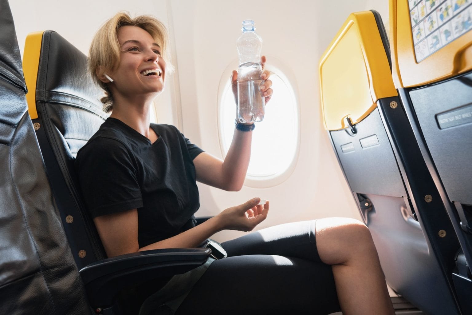 Young woman drinks water during her flight in an airplane