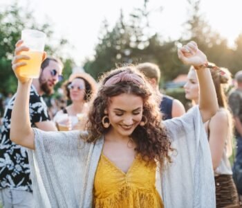 A young woman with drink dancing at summer festival