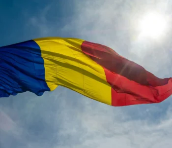 Beautiful low angle shot of the Romanian flag waving on a sunny bright sky background