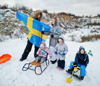 Scandinavian family with Sweden flag in winter swedish landscape.
