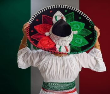 Woman shows Mexican hat with the colors of the Mexican flag. Mexican flag in background. Best Places to Visit in Mexico